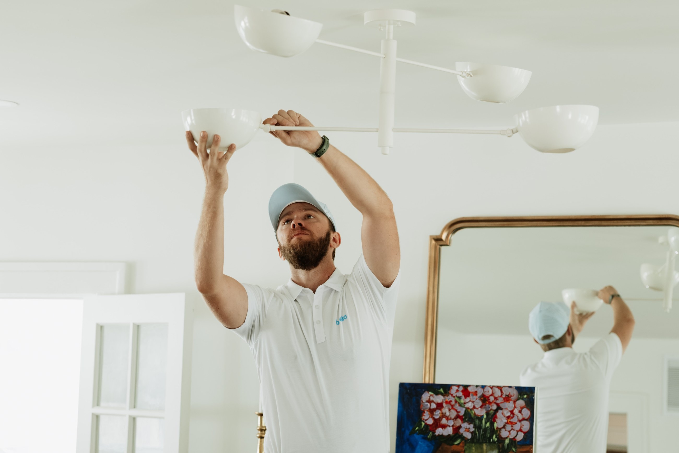 A Brella technician reaching up to fit a shade on a ceiling light fixture
